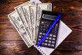 Notepad, pen, calculator and dollar bills on wooden table. Top v Royalty Free Stock Photo