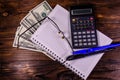 Notepad, pen, calculator and dollar bills on wooden table. Top v Royalty Free Stock Photo