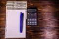 Notepad, pen, calculator and dollar bills on wooden table. Top v Royalty Free Stock Photo