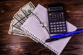 Notepad, pen, calculator and dollar bills on wooden table. Top v Royalty Free Stock Photo