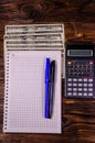 Notepad, pen, calculator and dollar bills on wooden table. Top v Royalty Free Stock Photo