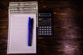 Notepad, pen, calculator and dollar bills on wooden table. Top v Royalty Free Stock Photo