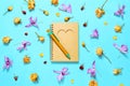 Notepad with pen and dried rose and orchids buds on blue background. Eco friendly materials concept Royalty Free Stock Photo