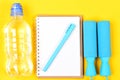 Notepad, pen and gym equipment top view on yellow background