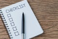 Notepad with pen and handwriting headline as Checklist with check box on wood table, to do list, tasks prioritize or finish or no