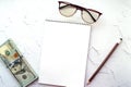 Notepad, pencil, glasses and us dollars on a light background