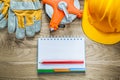 Notepad pencil protective gloves tape measure hard hat on wooden Royalty Free Stock Photo