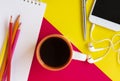 Notepad, pencils, coffee cup, headphones on the red and yellow background.