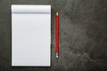 Notepad with a red pencil on a black stone plate background, for education, recording goals and deeds Royalty Free Stock Photo