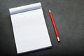 Notepad with a red pencil on a black stone plate background, for education, recording goals and deeds Royalty Free Stock Photo