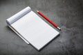 Notepad with a red pencil on a black stone plate background, for education, recording goals and deeds Royalty Free Stock Photo