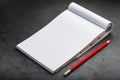 Notepad with a red pencil on a black stone plate background, for education, recording goals and deeds Royalty Free Stock Photo