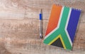 Notepad with South Africa flag, pen on wooden background