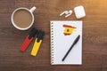 Notepad with spanish flag, wireless headphones, coffee cup, pen, markers on brown table