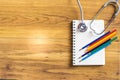 Notepad with stethoscope and pencil on wood board background.using wallpaper for education, business photo.Take note of the produc Royalty Free Stock Photo