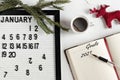Notepad for taking notes of goals and plans for the new year,calendar, a cup of coffee, Christmas tree decorations on the desktop Royalty Free Stock Photo
