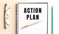 Notepad with text ACTION PLAN on a white background, near glasses and pencil Royalty Free Stock Photo