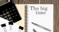 Notepad with text The big time on wooden background with clips, pen and calculator Royalty Free Stock Photo
