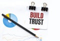 Notepad with text BUILD TRUST on business charts and pen Royalty Free Stock Photo