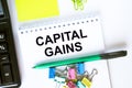 Notepad with text Capital Gains. Calculator, green pen stickers and stationary clips