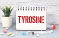 Notepad with the text and chemical structure of L Tyrosine on table with pills stethoscope