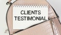 with text Client testimonials. A notebook peeks out of the pocket of a pink bag Royalty Free Stock Photo