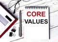 Notepad with text CORE VALUES, glasses, paper clips, white calculator and pen on desktop, top view Royalty Free Stock Photo