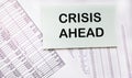 Notepad with the text A crisis is ahead against the backdrop of financial calculations. Economic crisis, business failure, Royalty Free Stock Photo