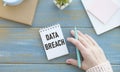 The text DATA BREACH on the table with notebook paper and hand Royalty Free Stock Photo