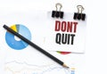 Notepad with text DONT QUIT on business charts and pen