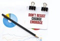 Notepad with text Dont resist change embrace on business charts and pen