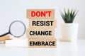 Notepad with text Dont resist change embrace on wooden block