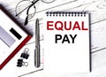 Notepad with text EQUAL PAY, glasses, paper clips, white calculator and pen on desktop, top view Royalty Free Stock Photo