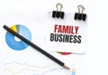 Notepad with text FAMILY BUSINESS on business charts and pen