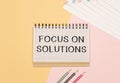 Notepad with text FOCUS ON SOLUTIONS on a white background