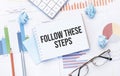 Notepad with text Follow these steps on the business charts and pen,business Royalty Free Stock Photo