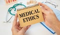 Notepad with text MEDICAL ETHICS in the hands of a doctor