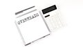 Notepad with text OVERHEADS with calculator and pen. White background. Business concept Royalty Free Stock Photo