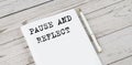 Notepad with text PAUSE AND REFLECT . White background. Business concept Royalty Free Stock Photo