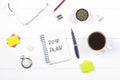 Notepad with the text: 2018 plan. White table with clock, cactus, paper for notes, coffee mug, pen, glasses. Royalty Free Stock Photo