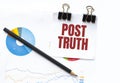 Notepad with text POST TRUTH on business charts and pen Royalty Free Stock Photo