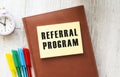 Notepad with text REFERRAL PROGRAM on a white background, near laptop, calculator.