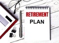 Notepad with text RETIREMENT PLAN, glasses, paper clips, white calculator and pen on desktop, top view Royalty Free Stock Photo