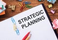 Notepad with the text - Strategic Planning on the table with colored paper clips and crumpled sheets Royalty Free Stock Photo