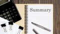 Notepad with text SUMMARY on the wooden background with clips, pen and calculator Royalty Free Stock Photo