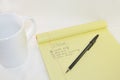 Notepad with White Coffee Mug and Black Ballpoint Pen on a White Background Royalty Free Stock Photo