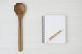 Notepad and wooden spoon on white wood table Royalty Free Stock Photo