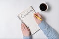 Notepad with word COACHING. Female hands and cup of coffee on white background. Top view