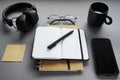 Notepads next to pen, sticky notes, cup of coffee, glasses, smartphone and headphones Royalty Free Stock Photo