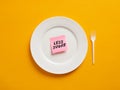 Notepaper with the word less sugar on a white plate. Less sugar intake and healthy nutrition Royalty Free Stock Photo